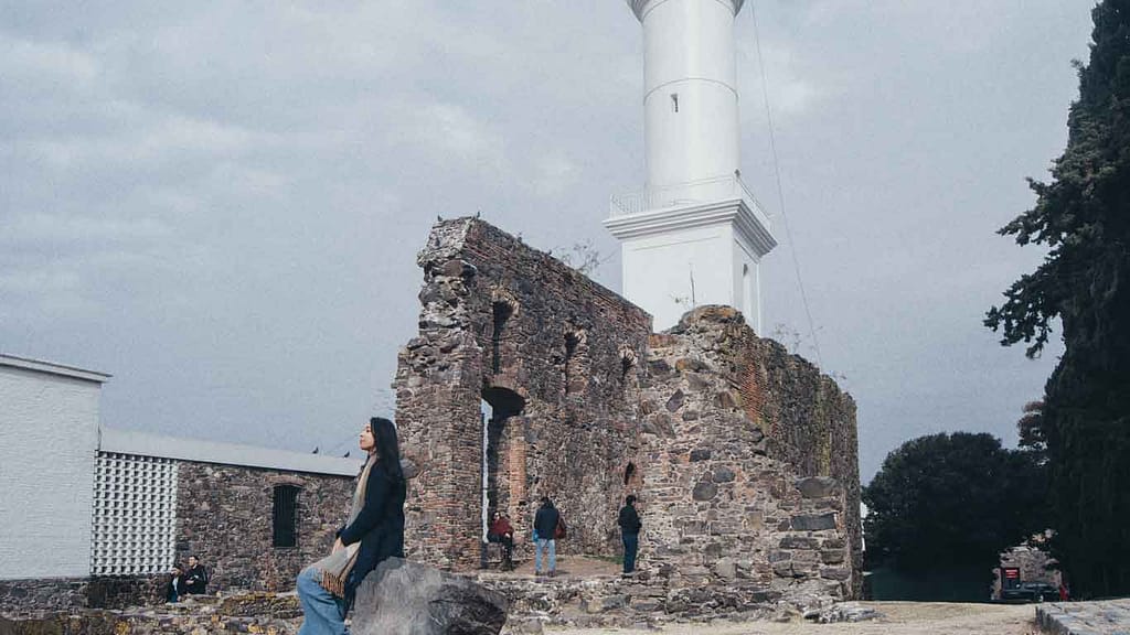Woman sitting in front of the Colonia del Sacramento Lighthouse in Uruguay